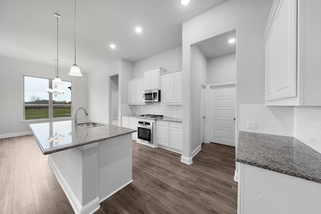 kitchen with stainless steel appliances, sink, white cabinetry, tasteful backsplash, and dark stone counters