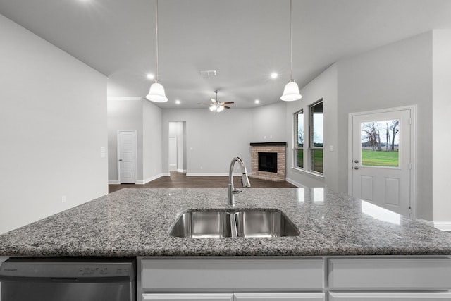 kitchen with dishwasher, ceiling fan, a fireplace, sink, and decorative light fixtures