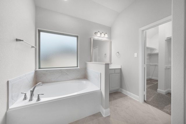 bathroom featuring vanity, tile patterned floors, a tub to relax in, and vaulted ceiling