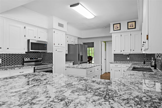 kitchen featuring white cabinets, appliances with stainless steel finishes, backsplash, and sink