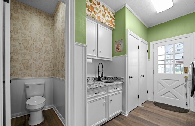 interior space with white cabinets, light stone counters, dark hardwood / wood-style flooring, sink, and a textured ceiling