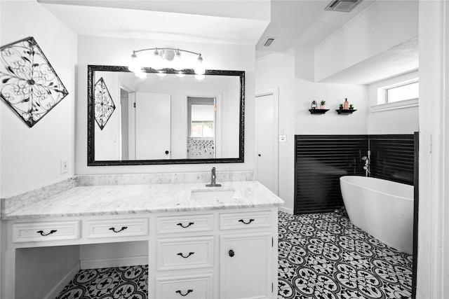 bathroom featuring tile patterned flooring, a washtub, and vanity