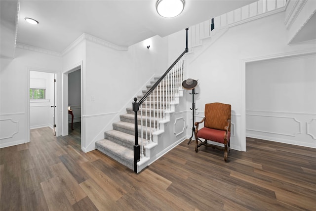 staircase with wood-type flooring and crown molding