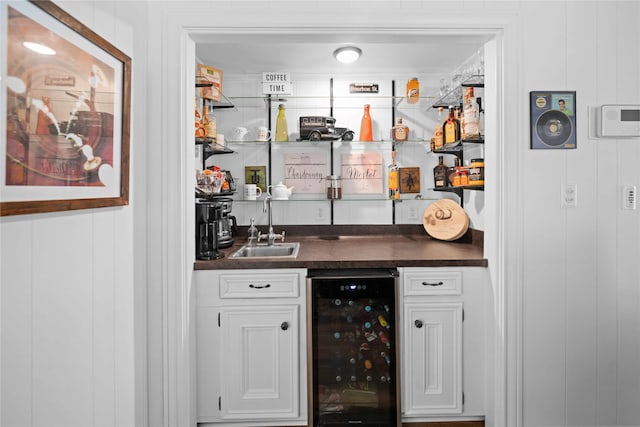 bar featuring beverage cooler, white cabinets, and sink