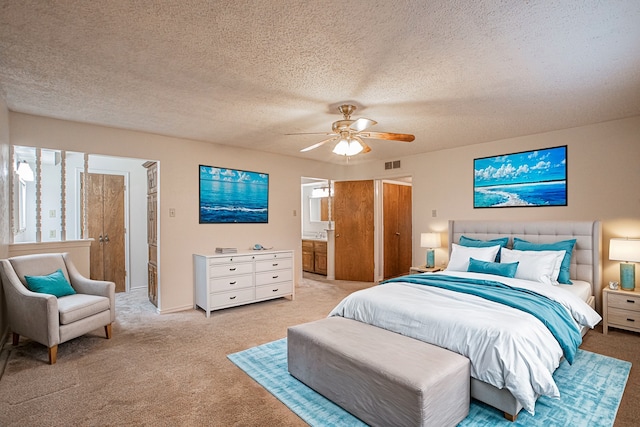 carpeted bedroom featuring ceiling fan, a textured ceiling, and ensuite bath