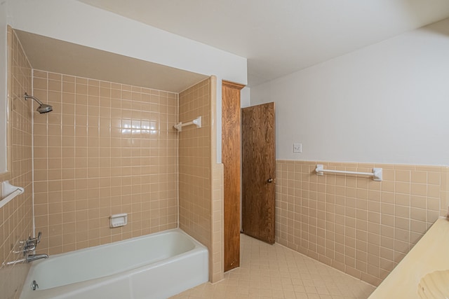 bathroom with tile patterned flooring, tile walls, and tiled shower / bath combo