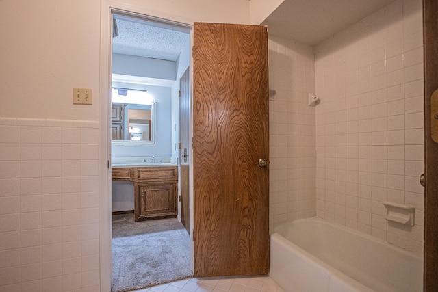 bathroom featuring tiled shower / bath, vanity, and a textured ceiling