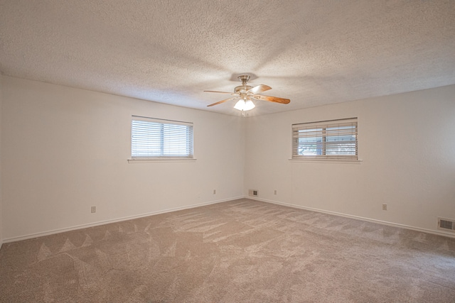 spare room featuring a textured ceiling, ceiling fan, and light colored carpet