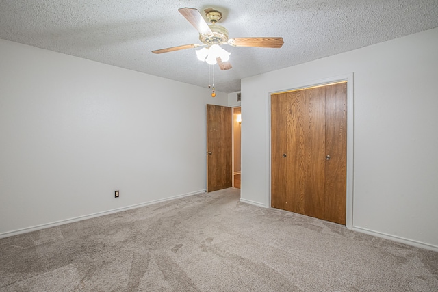 unfurnished bedroom with ceiling fan, a textured ceiling, a closet, and carpet flooring