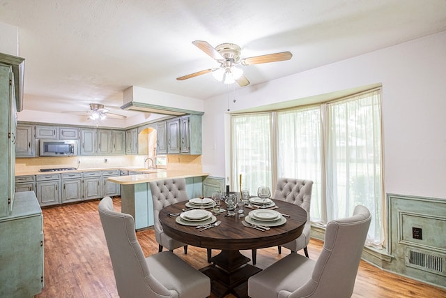 dining space featuring ceiling fan, light hardwood / wood-style flooring, and sink