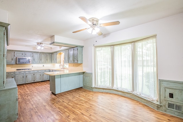 kitchen with ceiling fan, hardwood / wood-style floors, stainless steel appliances, sink, and kitchen peninsula