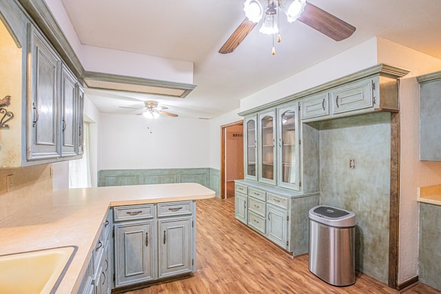 kitchen with kitchen peninsula, sink, light wood-type flooring, and ceiling fan