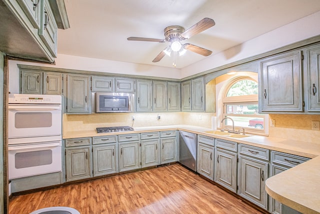 kitchen featuring light hardwood / wood-style floors, ceiling fan, sink, backsplash, and appliances with stainless steel finishes