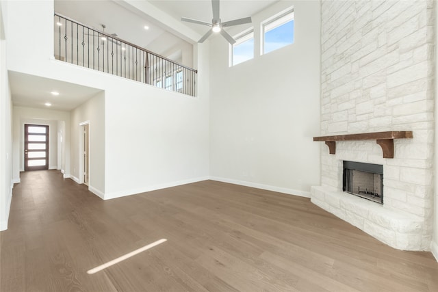 unfurnished living room with beam ceiling, a towering ceiling, wood-type flooring, and a fireplace