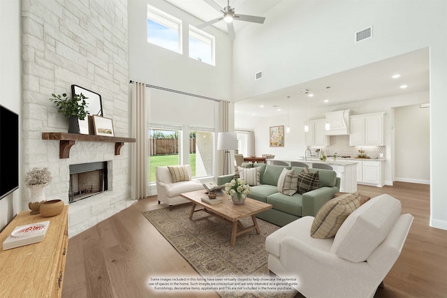 living room with light wood-type flooring, a high ceiling, plenty of natural light, and a fireplace