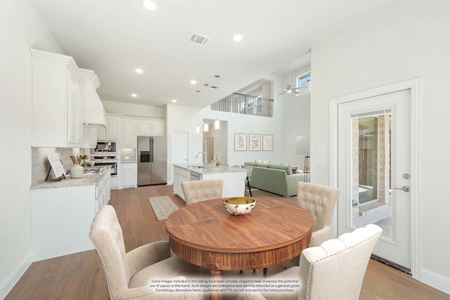 dining space with light hardwood / wood-style flooring, sink, and a high ceiling