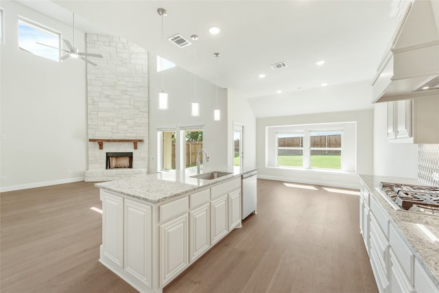 kitchen with white dishwasher, sink, pendant lighting, custom exhaust hood, and white cabinets