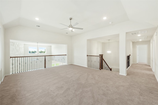 carpeted empty room with vaulted ceiling and ceiling fan with notable chandelier