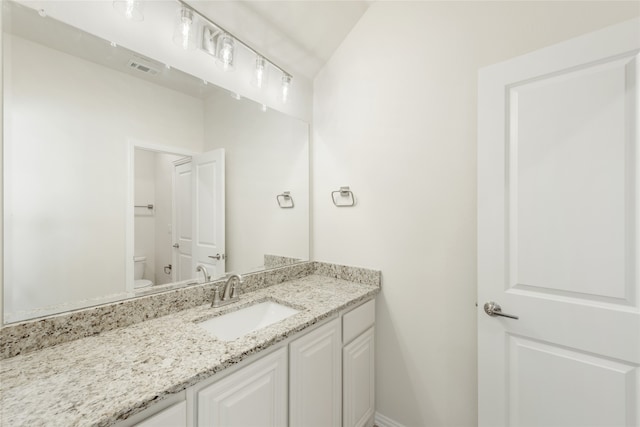 bathroom with vanity, toilet, and lofted ceiling