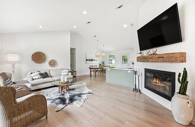 living room with high vaulted ceiling and light wood-type flooring