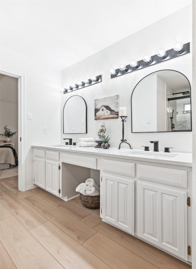 bathroom with a shower with door, vanity, and wood-type flooring