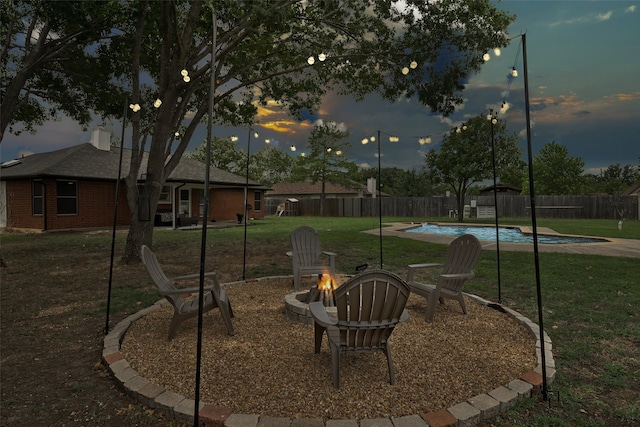 yard at dusk with a fenced in pool, a patio, and an outdoor fire pit