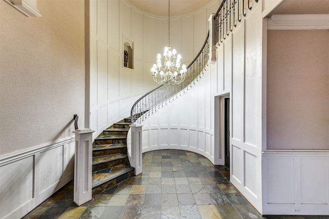 staircase featuring crown molding and an inviting chandelier