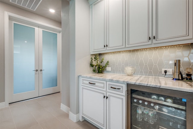 bar featuring light tile patterned flooring, beverage cooler, light stone counters, and tasteful backsplash