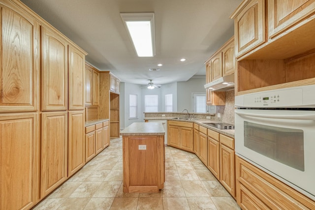 kitchen featuring black electric stovetop, sink, light brown cabinets, a center island, and oven