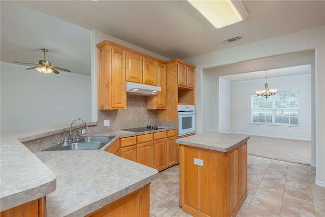 kitchen with oven, ceiling fan with notable chandelier, sink, black electric cooktop, and kitchen peninsula