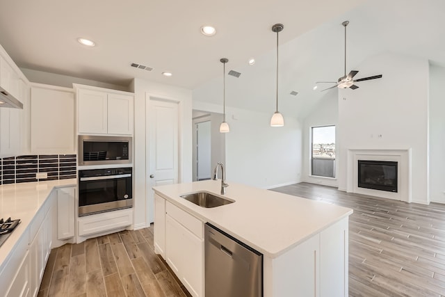 kitchen featuring white cabinetry, stainless steel appliances, sink, and a center island with sink