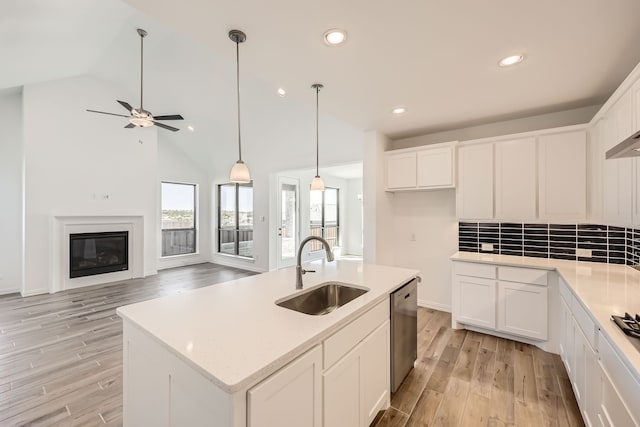 kitchen with white cabinetry, sink, light wood-type flooring, and a kitchen island with sink