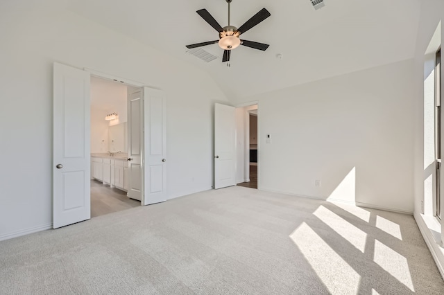 unfurnished bedroom featuring connected bathroom, ceiling fan, light carpet, and vaulted ceiling