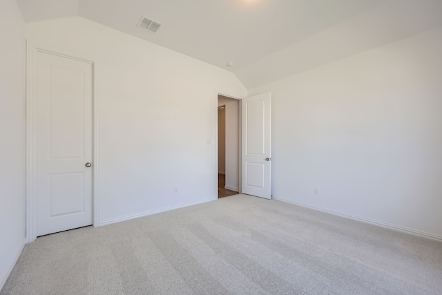 carpeted empty room featuring vaulted ceiling