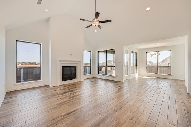 unfurnished living room featuring light hardwood / wood-style floors, ceiling fan with notable chandelier, and high vaulted ceiling