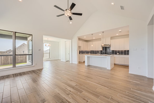 kitchen with white cabinets, high vaulted ceiling, light wood-type flooring, and pendant lighting