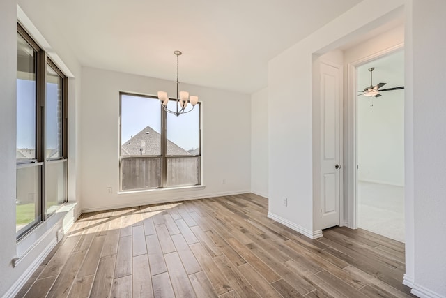 unfurnished dining area with hardwood / wood-style floors and ceiling fan with notable chandelier