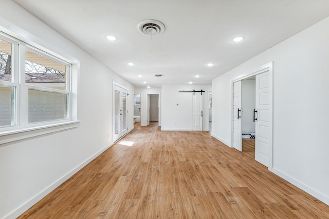 empty room with a barn door and light hardwood / wood-style floors