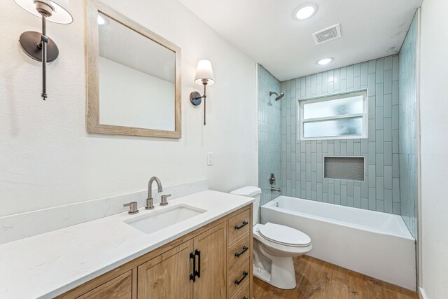 full bathroom with vanity, toilet, hardwood / wood-style flooring, and tiled shower / bath