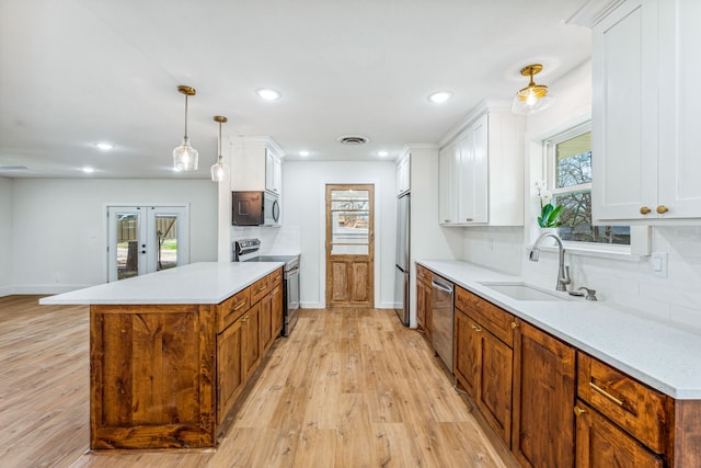 kitchen with hanging light fixtures, a healthy amount of sunlight, sink, and appliances with stainless steel finishes