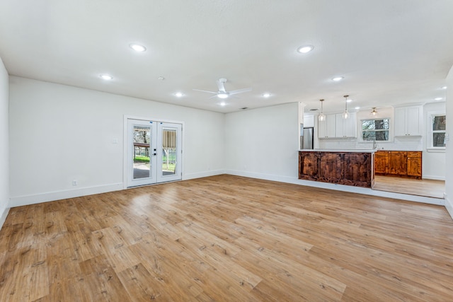 unfurnished living room with ceiling fan, sink, french doors, and light hardwood / wood-style floors