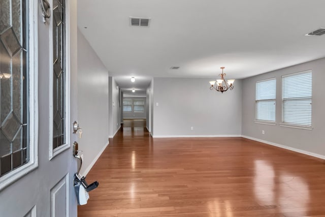 entrance foyer with a notable chandelier, light wood finished floors, and visible vents