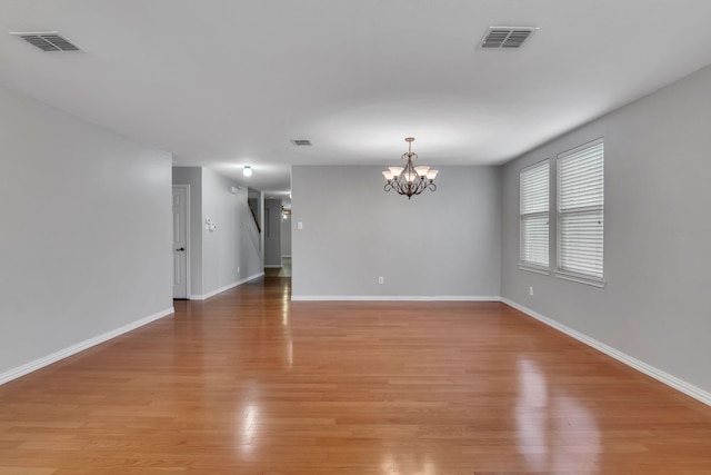 spare room featuring light hardwood / wood-style floors and a notable chandelier