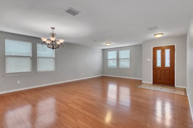 entrance foyer with visible vents, baseboards, a chandelier, and light wood-style floors