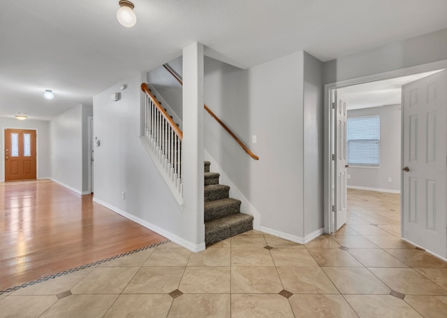 entrance foyer featuring light tile patterned flooring, baseboards, and stairs