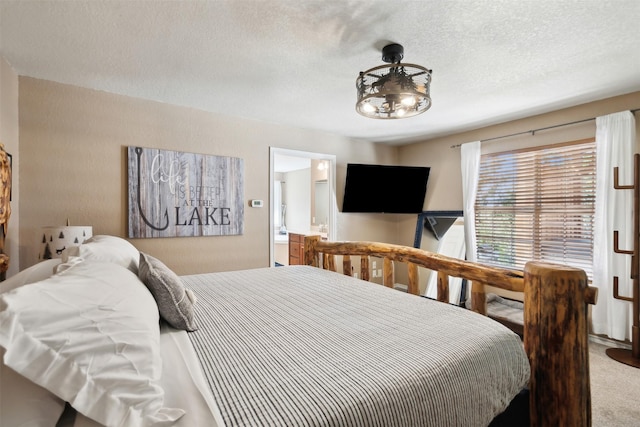 bedroom featuring ensuite bath, carpet flooring, and a textured ceiling