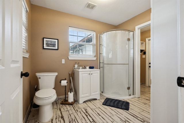 bathroom featuring visible vents, a shower stall, toilet, and wood finished floors