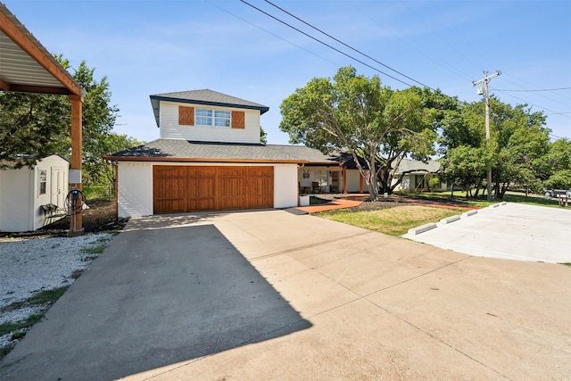 view of front facade featuring an attached garage, a storage shed, and driveway