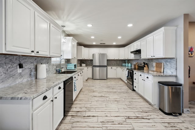 kitchen featuring light stone countertops, pendant lighting, appliances with stainless steel finishes, sink, and white cabinets