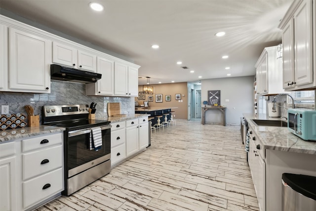 kitchen featuring decorative light fixtures, light stone counters, sink, appliances with stainless steel finishes, and white cabinets